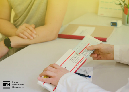 Врач показывает пациенту упаковку импланта эспераль